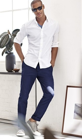 Как носить темно-синие брюки чинос с синей футболкой с круглым вырезом: Синяя футболка с круглым вырезом и темно-синие брюки чинос — хороший выбор, если ты хочешь создать простой, но в то же время модный мужской ансамбль. Вместе с этим луком органично выглядят серые кожаные низкие кеды.