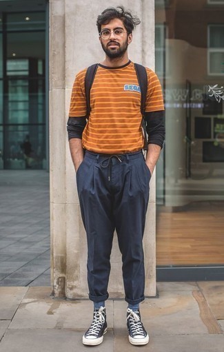 С чем носить оранжевую футболку с круглым вырезом в 30 лет мужчине в стиле кэжуал: Оранжевая футболка с круглым вырезом и темно-синие брюки чинос надежно закрепились в гардеробе многих парней, позволяя составлять яркие и стильные луки. Ты сможешь легко приспособить такой образ к повседневным условиям городской жизни, завершив его черно-белыми высокими кедами из плотной ткани.