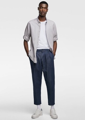 Модный лук: серая рубашка с длинным рукавом, белая футболка с круглым вырезом, темно-синие брюки чинос, белые кожаные низкие кеды