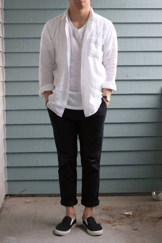 Как носить черные брюки чинос с белой рубашкой с длинным рукавом в стиле кэжуал: Белая рубашка с длинным рукавом выглядит выигрышно в паре с черными брюками чинос. Черные слипоны из плотной ткани — беспроигрышный выбор, чтобы закончить образ.