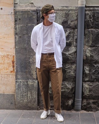 Модный лук: белая рубашка с длинным рукавом, белая футболка с круглым вырезом, светло-коричневые брюки чинос, белые низкие кеды из плотной ткани
