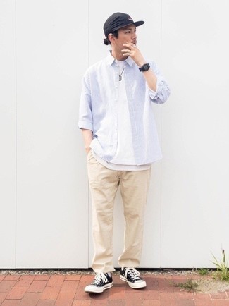 Модный лук: бело-синяя рубашка с длинным рукавом в вертикальную полоску, белая футболка с круглым вырезом, бежевые брюки чинос, черно-белые низкие кеды из плотной ткани