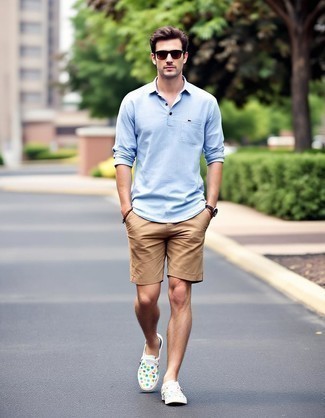 Модный мужской лук: голубая льняная рубашка с длинным рукавом, светло-коричневые шорты, разноцветные низкие кеды из плотной ткани с принтом, темно-коричневые солнцезащитные очки