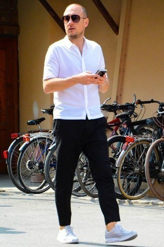 Модный лук: белая рубашка с коротким рукавом, черные брюки чинос, белые кроссовки, коричневые солнцезащитные очки