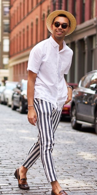Модный лук: белая рубашка с коротким рукавом, черно-белые брюки чинос в вертикальную полоску, темно-коричневые кожаные лоферы, светло-коричневая соломенная шляпа