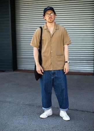 Модный лук: светло-коричневая рубашка с коротким рукавом, темно-синие джинсы, белые высокие кеды из плотной ткани, черная большая сумка из плотной ткани