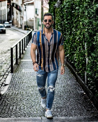 Как носить синие рваные зауженные джинсы с белыми низкими кедами мужчине: Если в одежде ты делаешь ставку на удобство и функциональность, темно-синяя рубашка с коротким рукавом в вертикальную полоску и синие рваные зауженные джинсы — замечательный выбор для стильного повседневного мужского лука. Хотел бы привнести в этот образ толику эффектности? Тогда в качестве дополнения к этому ансамблю, стоит выбрать белые низкие кеды.