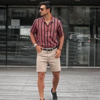 Модный лук: красная рубашка с коротким рукавом в вертикальную полоску, бежевые джинсовые шорты, черные низкие кеды из плотной ткани, черный кожаный ремень