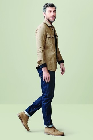 Как носить темно-синие джинсы с светло-коричневыми замшевыми ботинками дезертами за 40 лет в теплую погоду в стиле кэжуал: Светло-коричневая куртка-рубашка и темно-синие джинсы — необходимые вещи в арсенале парней с превосходным вкусом в одежде. Говоря об обуви, можно дополнить образ светло-коричневыми замшевыми ботинками дезертами.