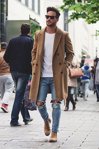 С чем носить бежевую замшевую обувь мужчине в холод: Светло-коричневое длинное пальто в паре с голубыми рваными джинсами — превосходная идея для воплощения мужского ансамбля в стиле smart casual. Такой образ получает свежее прочтение в тандеме с светло-коричневыми замшевыми ботинками челси.