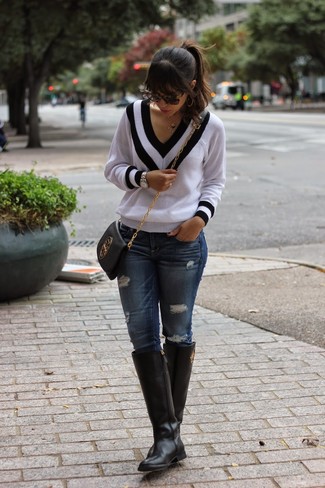 Модный лук: бело-черный свитер с v-образным вырезом, темно-синие рваные джинсы скинни, черные кожаные сапоги, черная кожаная сумка через плечо
