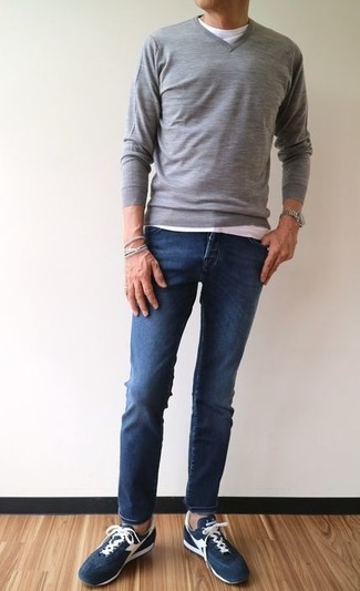 Какие зауженные джинсы носить с серым свитером с v-образным вырезом мужчине: Образ из серого свитера с v-образным вырезом и зауженных джинсов как нельзя лучше подчеркнет твою мужественность. Темно-синие замшевые низкие кеды прекрасно впишутся в лук.