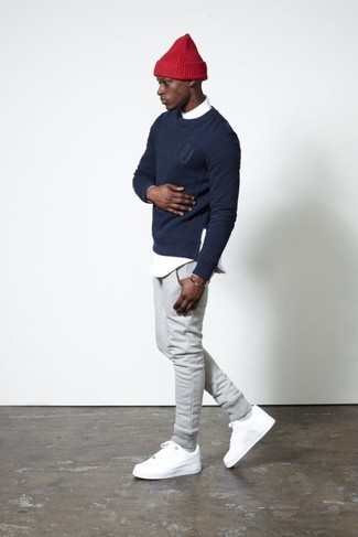 Модный лук: темно-синий свитер с круглым вырезом с принтом, белая рубашка с длинным рукавом, серые спортивные штаны, белые низкие кеды