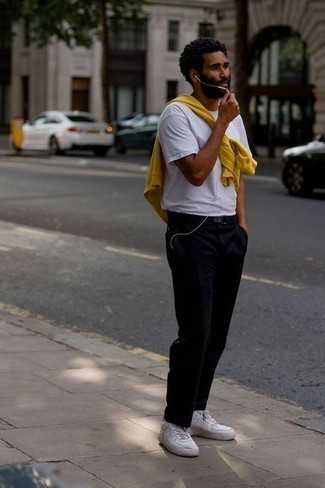 С чем носить черные вельветовые брюки чинос: Желтый свитшот и черные вельветовые брюки чинос — прекрасный вариант для простого, но стильного мужского образа. Белые кожаные низкие кеды отлично дополнят этот образ.