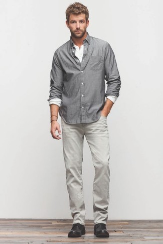 Модный лук: серая рубашка с длинным рукавом, белая лонгслив с горловиной на пуговицах, серые джинсы, черные кожаные ботинки дезерты