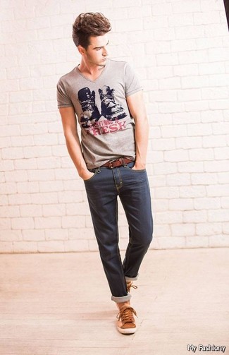 Модный лук: серая футболка с v-образным вырезом с принтом, темно-синие зауженные джинсы, коричневые кожаные низкие кеды, коричневый кожаный ремень