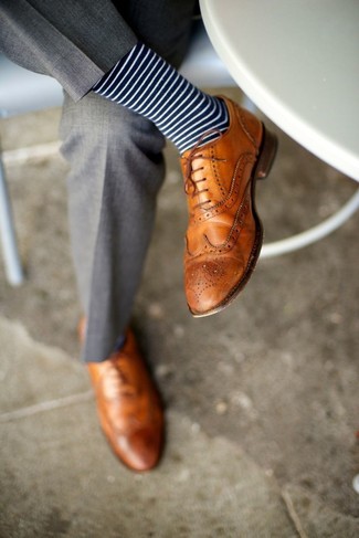 С чем носить светло-коричневые кожаные броги: Серые классические брюки — великолепный пример строгого мужского стиля в одежде. Дополнив образ светло-коричневыми кожаными брогами, ты привнесешь в него немного непринужденности.
