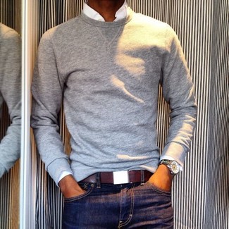 Модный лук: серый свитер с круглым вырезом, белая рубашка с длинным рукавом, темно-синие джинсы, темно-красный кожаный ремень