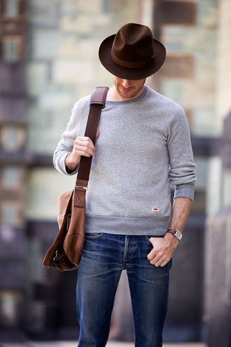 С чем носить темно-коричневую шерстяную шляпу мужчине: Для активного дня в компании друзей великолепно подойдет сочетание серого свитера с круглым вырезом и темно-коричневой шерстяной шляпы.