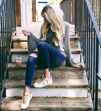 С чем носить синие рваные джинсы скинни в теплую погоду: Серый свитер с круглым вырезом и синие рваные джинсы скинни — хорошее решение для дам, которые всегда в движении. Белые кожаные низкие кеды — беспроигрышный выбор, чтобы закончить лук.