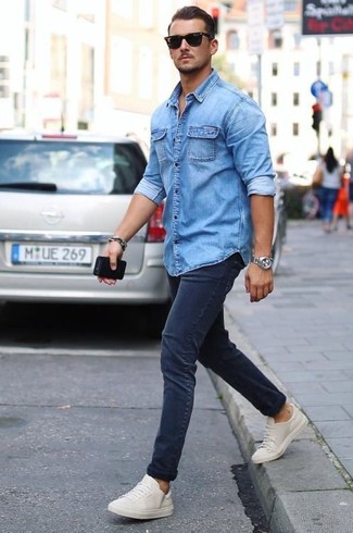 Как носить темно-синюю джинсовую рубашку с темно-синими зауженными джинсами мужчине в теплую погоду в стиле кэжуал: Если ты делаешь ставку на комфорт и практичность, темно-синяя джинсовая рубашка и темно-синие зауженные джинсы — замечательный выбор для модного повседневного мужского ансамбля. Что же до обуви, белые низкие кеды — самый удачный вариант.