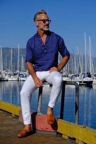 С чем носить бело-темно-синие брюки чинос за 50 лет в жару в стиле кэжуал: Синяя льняная рубашка с длинным рукавом и бело-темно-синие брюки чинос — необходимые элементы в гардеробе джентльменов с превосходным вкусом в одежде. Табачные кожаные мокасины стильно впишутся в лук.