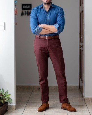 Как носить темно-красные брюки чинос с темно-коричневыми замшевыми ботинками дезертами осень: Синяя рубашка с длинным рукавом из шамбре и темно-красные брюки чинос надежно обосновались в гардеробе современных мужчин, позволяя создавать неприевшиеся и комфортные образы. Темно-коричневые замшевые ботинки дезерты — прекрасный вариант, чтобы завершить образ. Разве это не классная задумка в тоскливый осенний день?