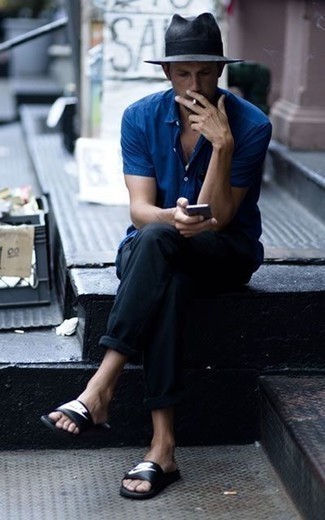 Модный лук: синяя рубашка с коротким рукавом, черные брюки чинос, черно-белые кожаные сандалии с принтом, темно-серая соломенная шляпа