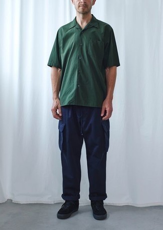 С чем носить темно-зеленую рубашку за 40 лет мужчине: Образ из темно-зеленой рубашки и темно-синих брюк карго позволит реализовать в твоем луке городской стиль современного джентльмена. Хочешь сделать образ немного элегантнее? Тогда в качестве обуви к этому луку, стоит обратить внимание на черные замшевые низкие кеды.