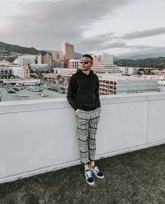 Модный мужской лук: темно-зеленый худи, серые брюки чинос в шотландскую клетку, черно-белые низкие кеды из плотной ткани в клетку, темно-коричневые солнцезащитные очки