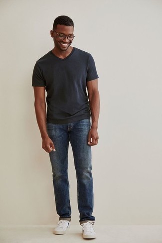Как носить синие джинсы с бело-черными низкими кедами из плотной ткани в 20 лет мужчине в жару: Темно-серая футболка с v-образным вырезом и синие джинсы будут отлично смотреться в стильном гардеробе самых избирательных парней. В сочетании с этим образом отлично выглядят бело-черные низкие кеды из плотной ткани.