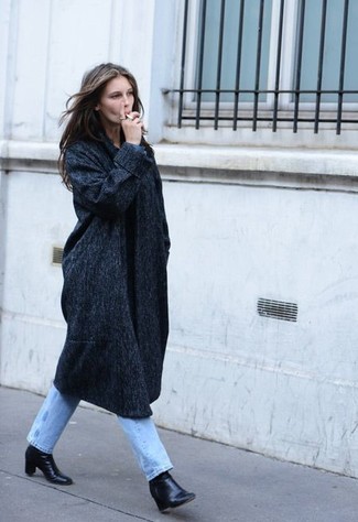С чем носить обувь в холод в деловом стиле: Сочетание темно-серого пальто и голубых джинсов ориентировано на современную женщину, ведущую активный образ жизни. Пара черных кожаных ботильонов гармонично интегрируется в этот ансамбль.