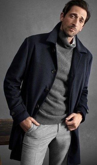 Как носить темно-синее длинное пальто с серыми шерстяными классическими брюками за 50 лет: Темно-синее длинное пальто в паре с серыми шерстяными классическими брюками позволит реализовать строгий деловой стиль.