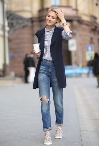 С чем носить синие рваные джинсы-бойфренды в 20 лет: Если ты любишь выглядеть красиво и при этом чувствовать себя комфортно и нескованно, примерь это сочетание темно-синего пальто без рукавов и синих рваных джинсов-бойфрендов. Пара серых кожаных низких кед выигрышно вписывается в этот наряд.