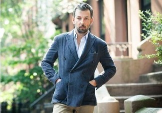 Сочетание темно-синего двубортного пиджака и светло-коричневых брюк чинос — превосходный пример непринужденного офисного стиля для молодых людей.
