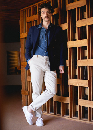 Как носить темно-синий двубортный пиджак с светло-коричневыми брюками чинос лето: Темно-синий двубортный пиджак и светло-коричневые брюки чинос выигрышно впишутся в любой мужской образ — простой повседневный образ или же строгий вечерний. Если ты любишь более практичную обувь, останови свой выбор на белых низких кедах из плотной ткани. Пережить изнуряющую летнюю жару будет значительно проще, когда на тебе такое сочетание одежды.