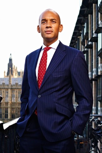 С чем носить красный галстук в горошек мужчине в теплую погоду в деловом стиле: Темно-синий костюм в вертикальную полоску в паре с красным галстуком в горошек поможет воплотить строгий деловой стиль.