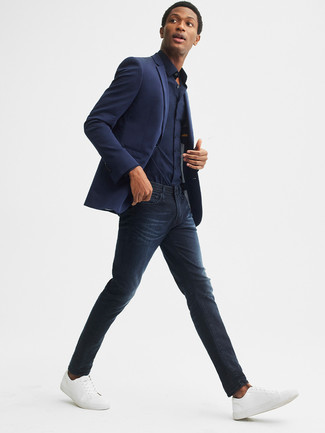 Как носить синий пиджак с синими зауженными джинсами в 20 лет мужчине лето в стиле смарт-кэжуал: Синий пиджак в сочетании с синими зауженными джинсами продолжает импонировать джентльменам, которые любят одеваться с иголочки. В паре с этим образом наиболее удачно выглядят белые кожаные низкие кеды. Подобный образ обязательно придется тебе по вкусу в знойные летние дни.