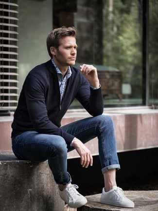 Как носить темно-синие джинсы с бело-черными кожаными низкими кедами в 30 лет мужчине: Темно-синий свитер на молнии в паре с темно-синими джинсами — отличный вариант для создания мужского образа в элегантно-деловом стиле. Бело-черные кожаные низкие кеды становятся замечательным дополнением к твоему ансамблю.