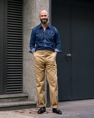 Как носить черные кожаные лоферы с темно-синей джинсовой рубашкой мужчине в стиле смарт-кэжуал: Темно-синяя джинсовая рубашка и светло-коричневые брюки чинос — хороший вариант, если ты ищешь раскованный, но в то же время стильный мужской лук. Любишь экспериментировать? Закончи образ черными кожаными лоферами.