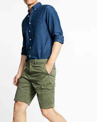 С чем носить темно-зеленые шорты в 20 лет мужчине в стиле кэжуал: Лук из темно-синей рубашки с длинным рукавом из шамбре и темно-зеленых шорт — великолепный пример современного стиля в большом городе.