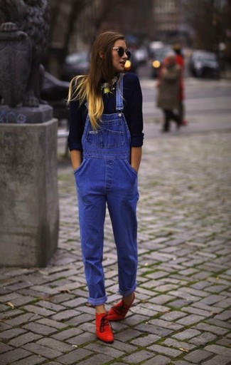 С чем носить синие джинсовые комбинезон в 30 лет: Темно-синяя футболка с длинным рукавом и синие джинсовые штаны-комбинезон будет превосходным вариантом для расслабленного повседневного образа. В сочетании с этим образом наиболее выгодно будут выглядеть красные замшевые ботильоны.