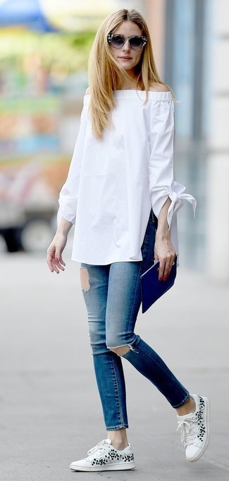 Как Olivia Palermo носит Белый топ с открытыми плечами, Синие рваные джинсы скинни, Белые низкие кеды с цветочным принтом, Синий кожаный клатч