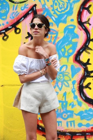 Модный лук: белый топ с открытыми плечами, бежевые льняные шорты, черные солнцезащитные очки, разноцветный браслет с геометрическим рисунком