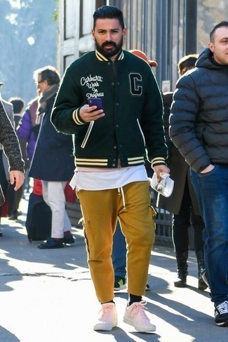 С чем носить зелено-желтые брюки в 30 лет мужчине: Темно-зеленая университетская куртка и зелено-желтые брюки прочно закрепились в гардеробе современных молодых людей, помогая составлять яркие и комфортные образы. Преобразить ансамбль и добавить в него чуточку классики помогут розовые кожаные низкие кеды.