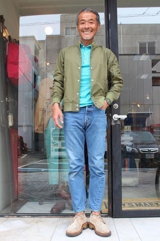 Как носить темно-зеленую университетскую куртку с темно-синими джинсами за 50 лет мужчине: Сочетание темно-зеленой университетской куртки и темно-синих джинсов не прекращает импонировать мужчинам, которые любят одеваться со вкусом. Любишь эксперименты? Дополни ансамбль бежевыми замшевыми ботинками дезертами.