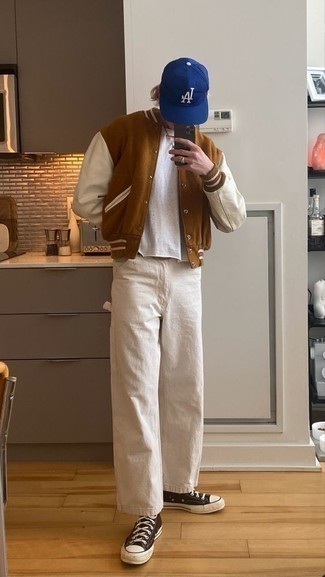 С чем носить коричневые высокие кеды мужчине: Коричневая университетская куртка и бежевые джинсы — отличный выбор, если ты хочешь создать расслабленный, но в то же время стильный мужской образ. Любишь дерзкие решения? Тогда закончи свой образ коричневыми высокими кедами.