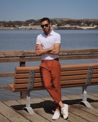Как носить оранжевые брюки чинос с белыми кожаными низкими кедами: Белая футболка-поло и оранжевые брюки чинос — обязательные вещи в гардеробе современного парня. В тандеме с этим образом выигрышно выглядят белые кожаные низкие кеды.