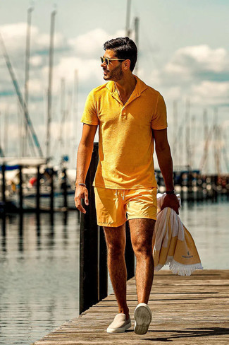 Модный лук: горчичная футболка-поло, горчичные шорты для плавания, бежевые замшевые слипоны, темно-коричневые солнцезащитные очки