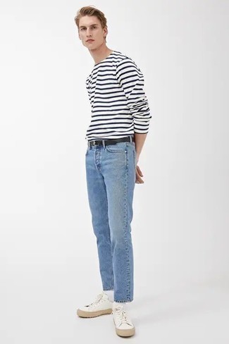 Модный лук: бело-темно-синяя футболка с длинным рукавом в горизонтальную полоску, голубые джинсы, белые низкие кеды из плотной ткани, черный кожаный ремень